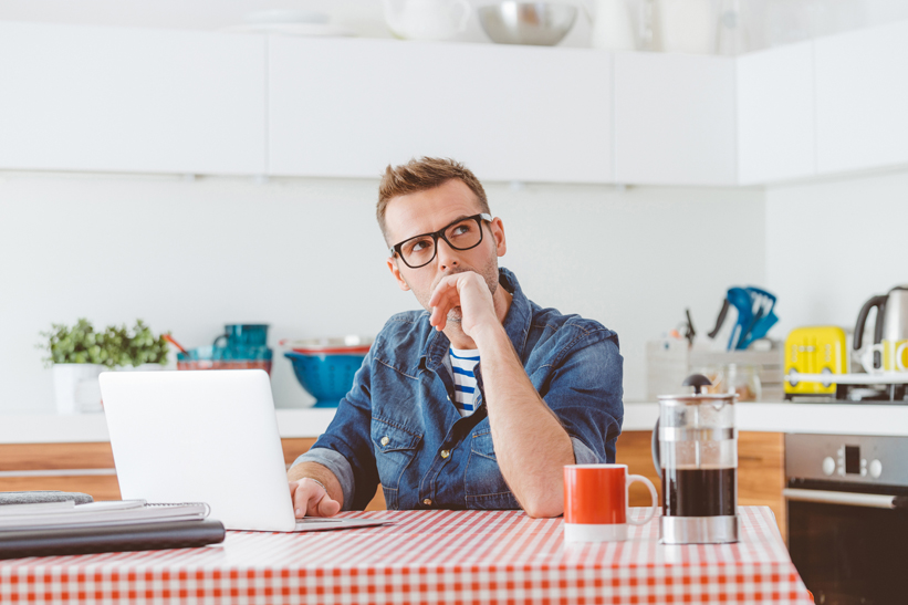Man using laptop in a domestic kitchen